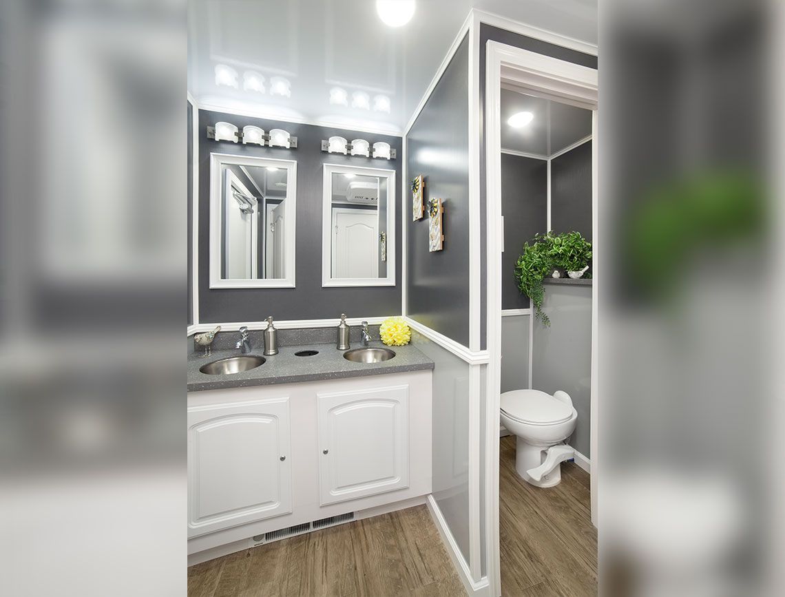 Bright bathroom with white vanity, double mirrors, and a glimpse of the toilet room