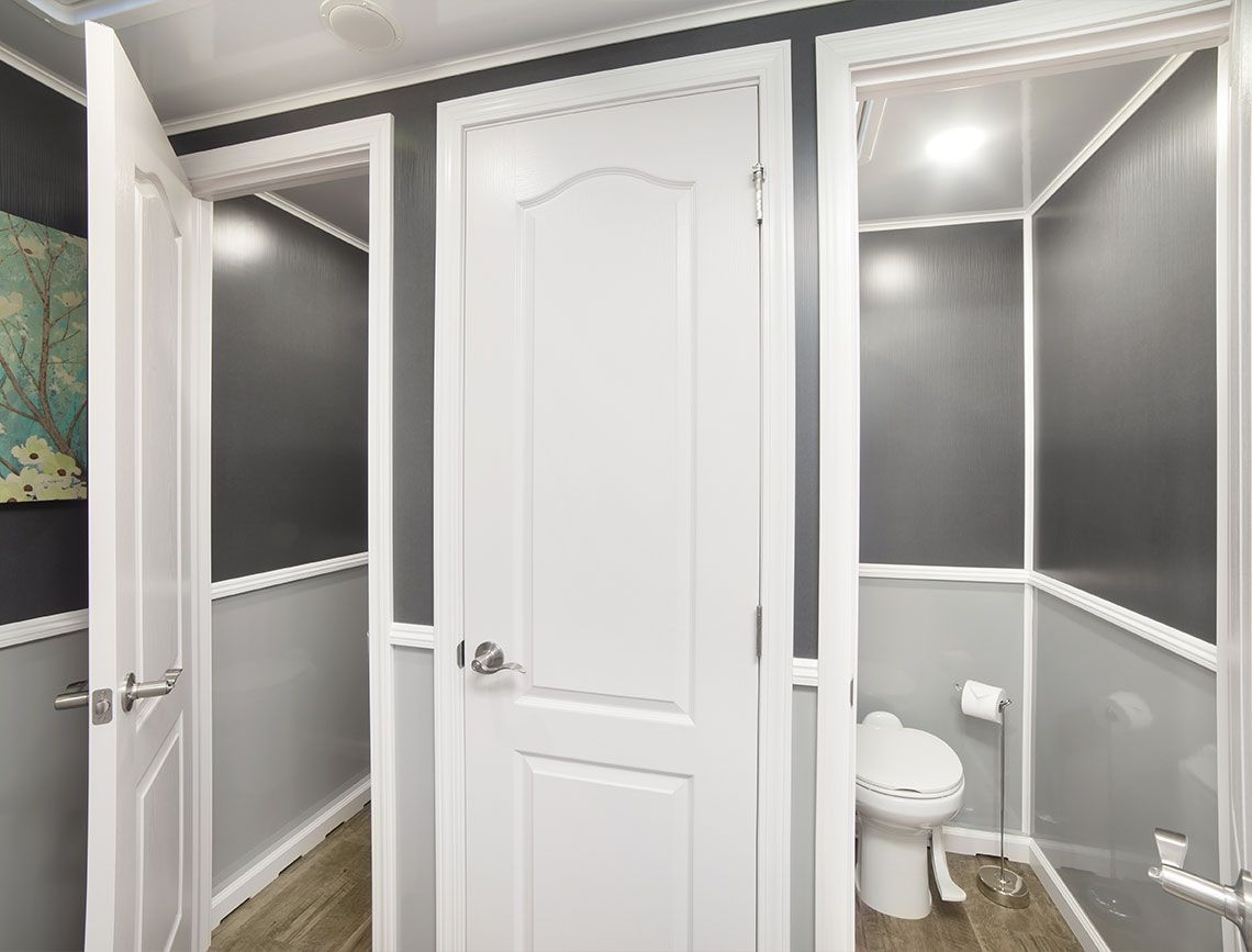 Small gray bathroom with white trim, a toilet, and a central white door.