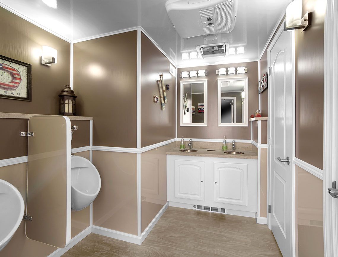 Accessible beige-and-white bathroom with double vanity, mirrors, urinal, and stall divider.