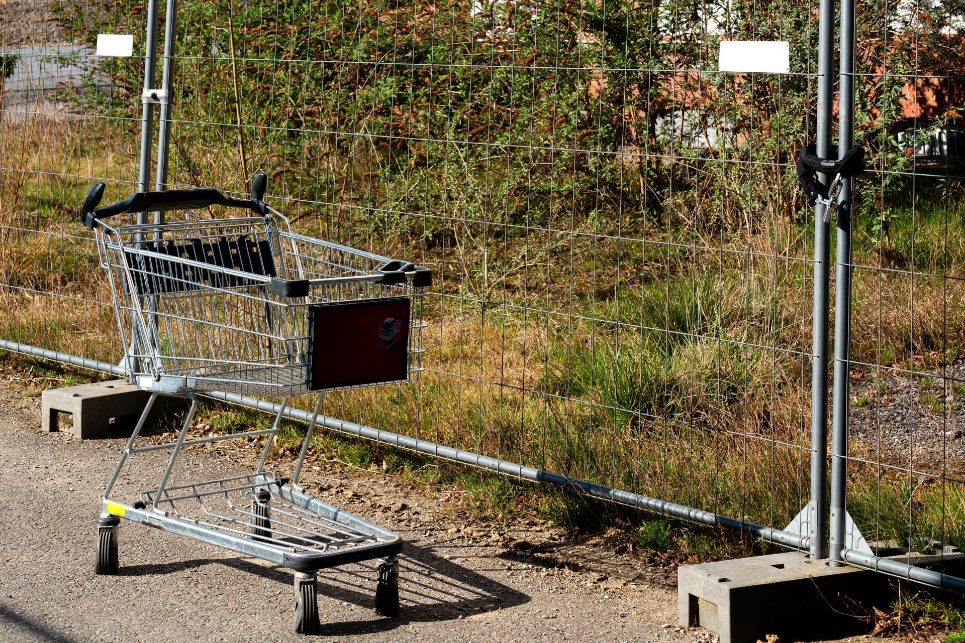 Shopping cart next to a construction fence on a sunny day. Shopping cart next to a construction fence on a sunny day.