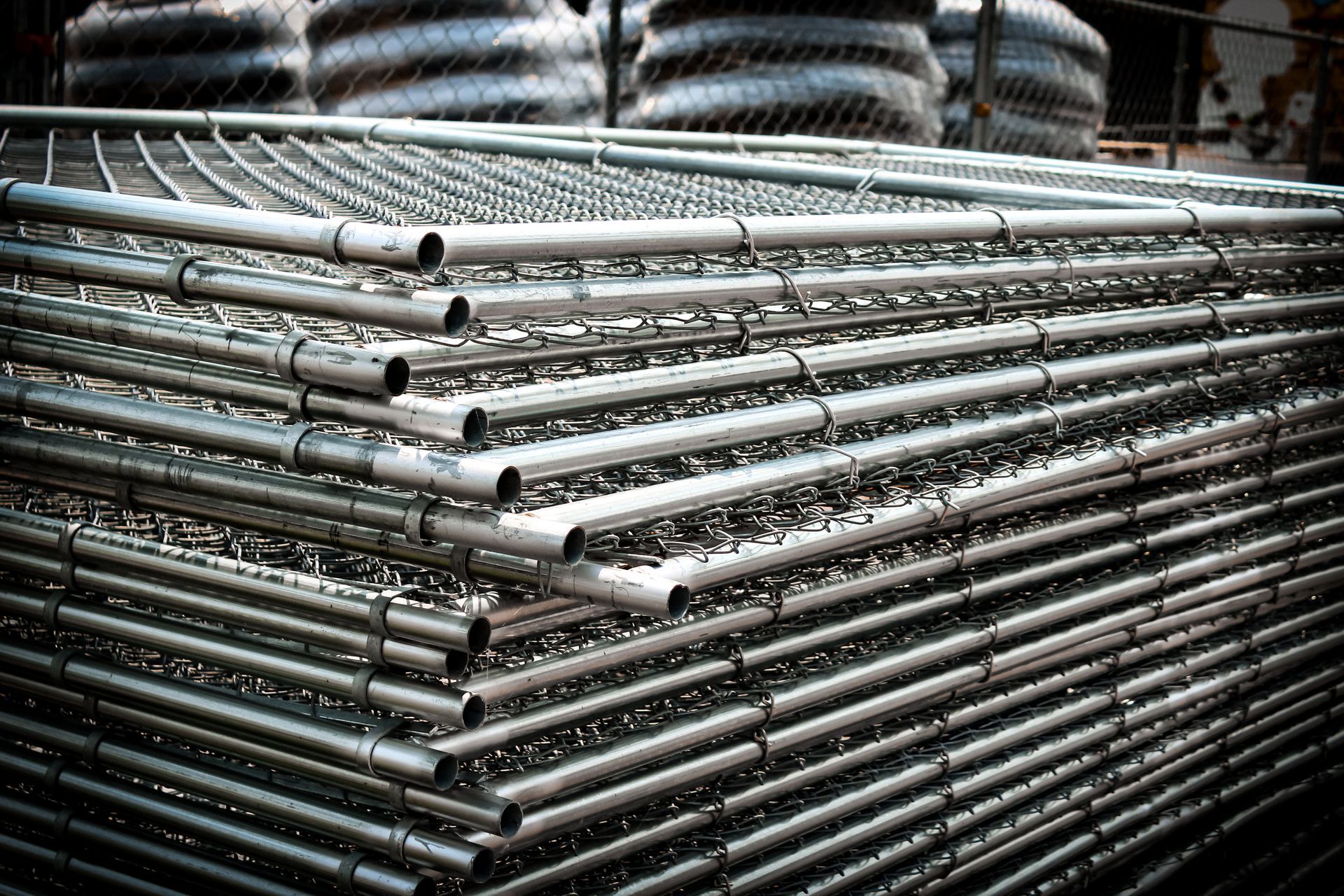 Stacked, galvanized metal chain-link fence panels. Stacked, galvanized metal chain-link fence panels.