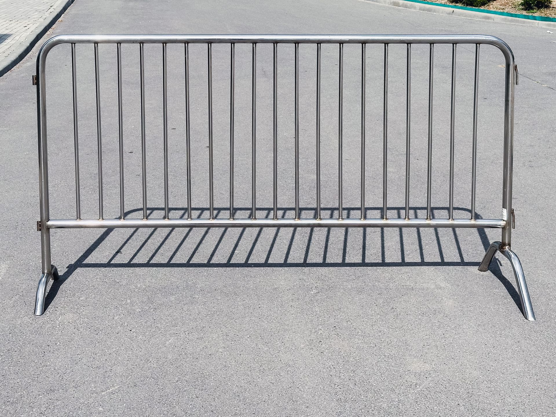 Metal barricade on an empty street pavement in daylight.
