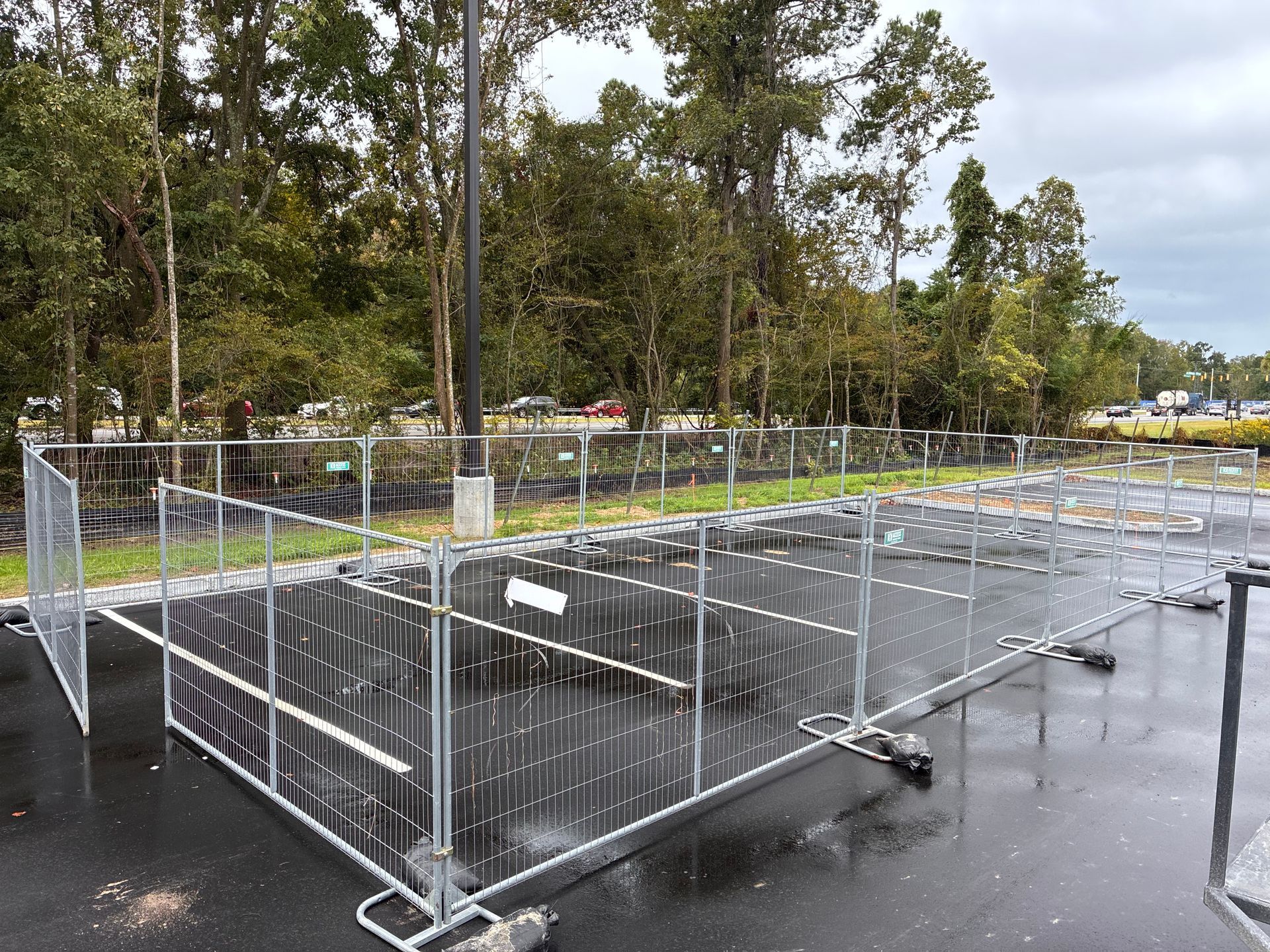 Metal crowd-control barriers lined up on wet pavement in an outdoor park area