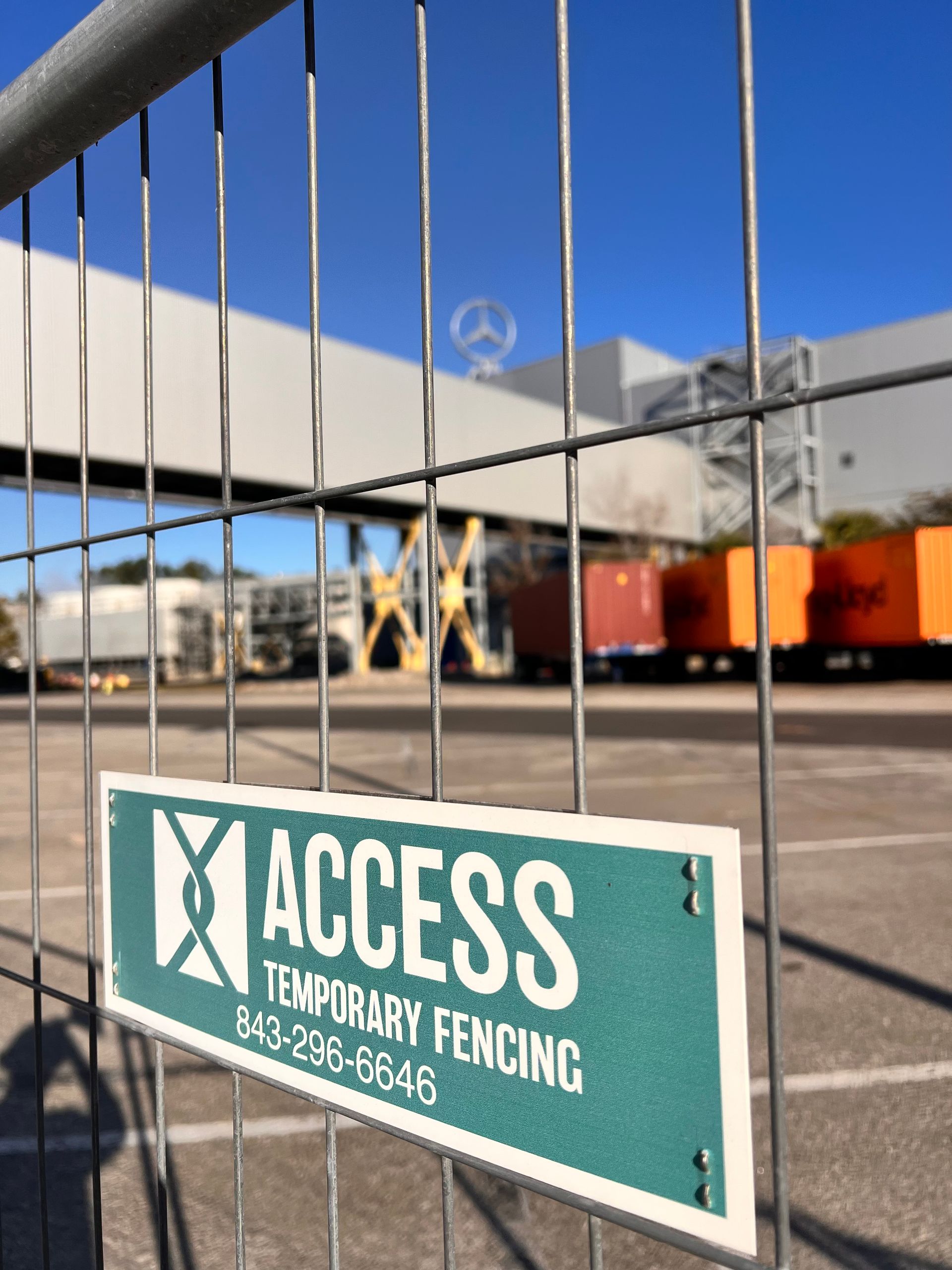 Temporary fencing with an ACCESS sign at a construction site under a blue sky.