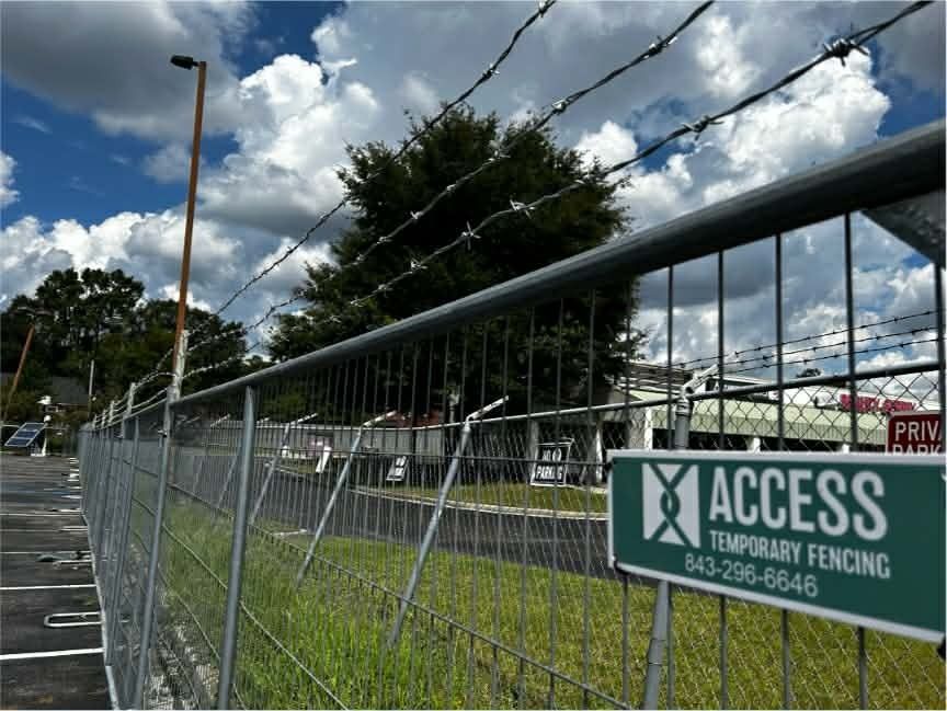 Temporary chain-link fencing along a roadside under a cloudy sky, with an ACCESS sign.
