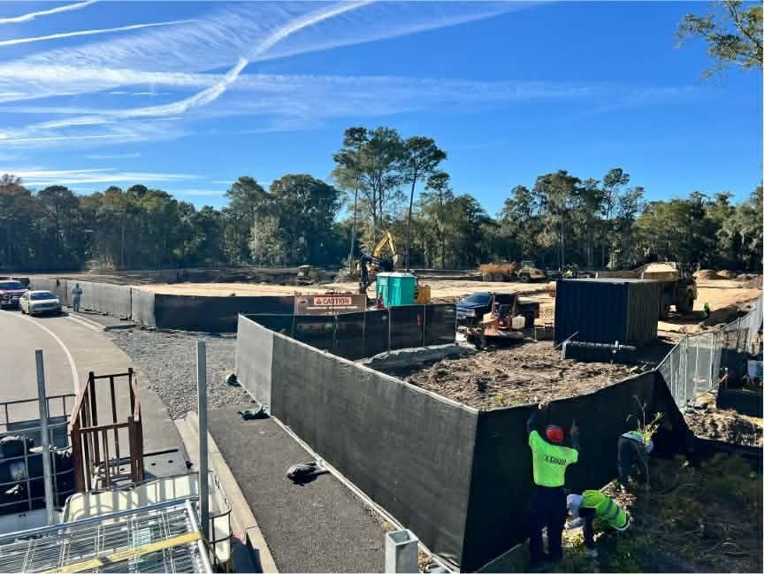 Construction site with workers building concrete walls under a blue sky