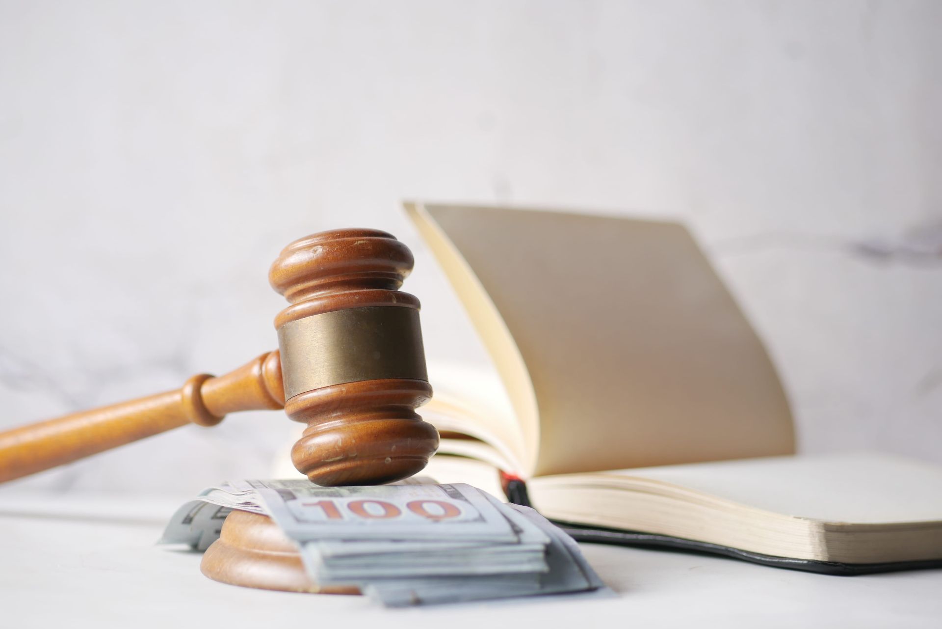 Judge’s gavel beside a stack of euro banknotes and an open book on a desk