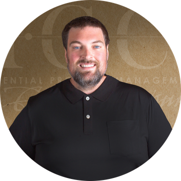 Man with short hair and a beard, wearing a black collared shirt, smiling.