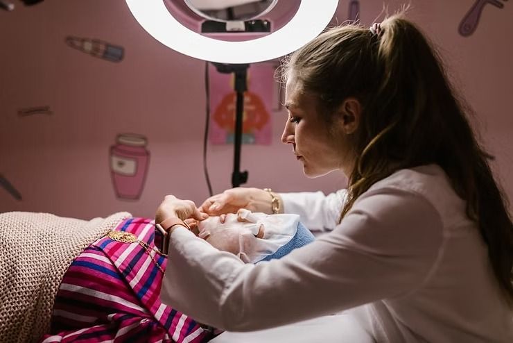 Woman holding a newborn under a ring light in a pink nursery