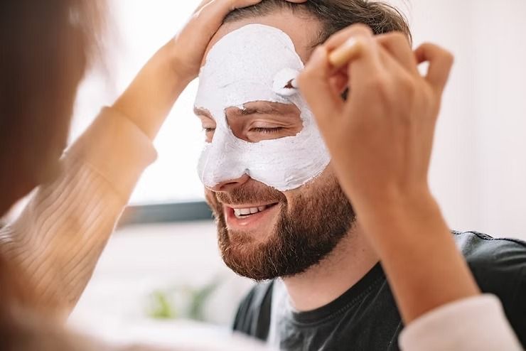 Person applying a white face mask while smiling indoors