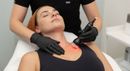 Woman with pink-gloved hands framing her face in a beauty salon close-up