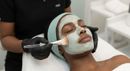 Facial treatment with gloved hands applying cream to a client lying on a spa bed