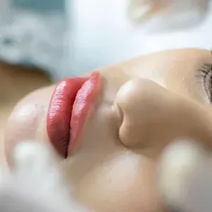 Woman with a white facial mask and towel wrapped around her head in a spa setting