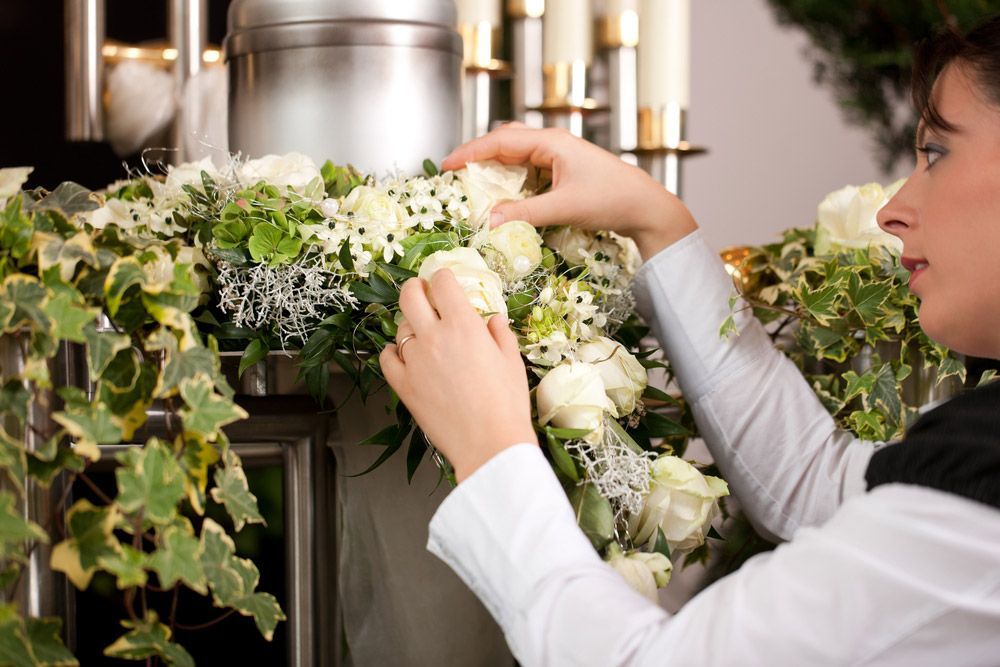 A Woman Worker Mortician On Funeral With Urn Preparing The Flowers — Explore Our Services For Cremation in Sydney, NSW