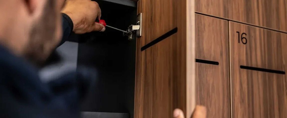 A man is working on a wooden cabinet with a screwdriver.