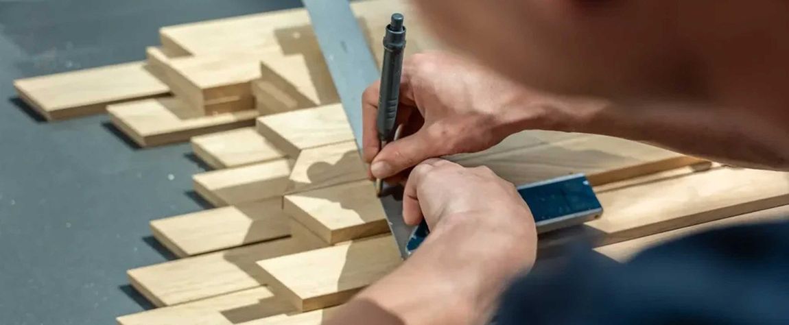 A man is measuring a piece of wood with a tape measure.