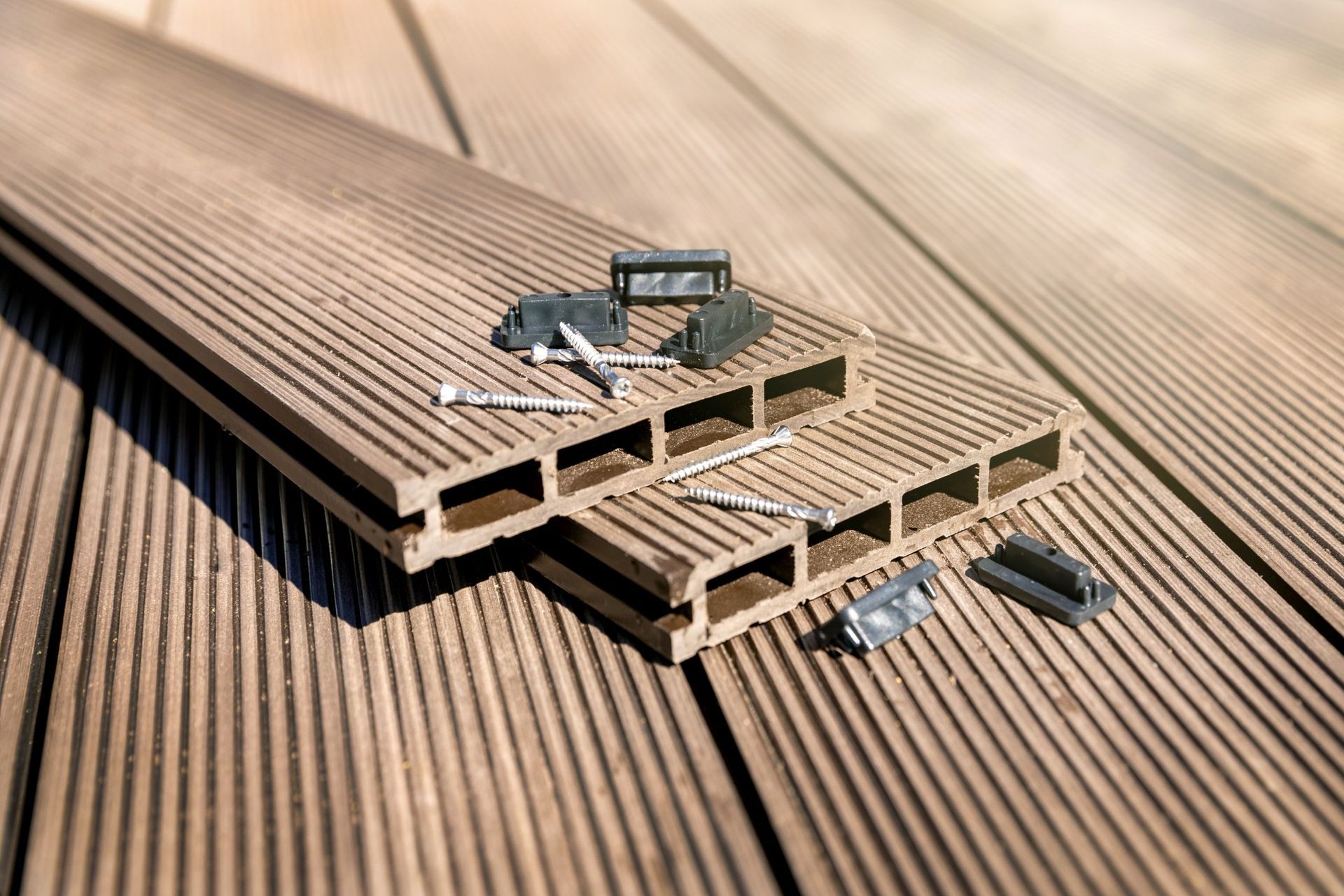 Wooden decking boards, with a cross-section sample and small hardware pieces on top.