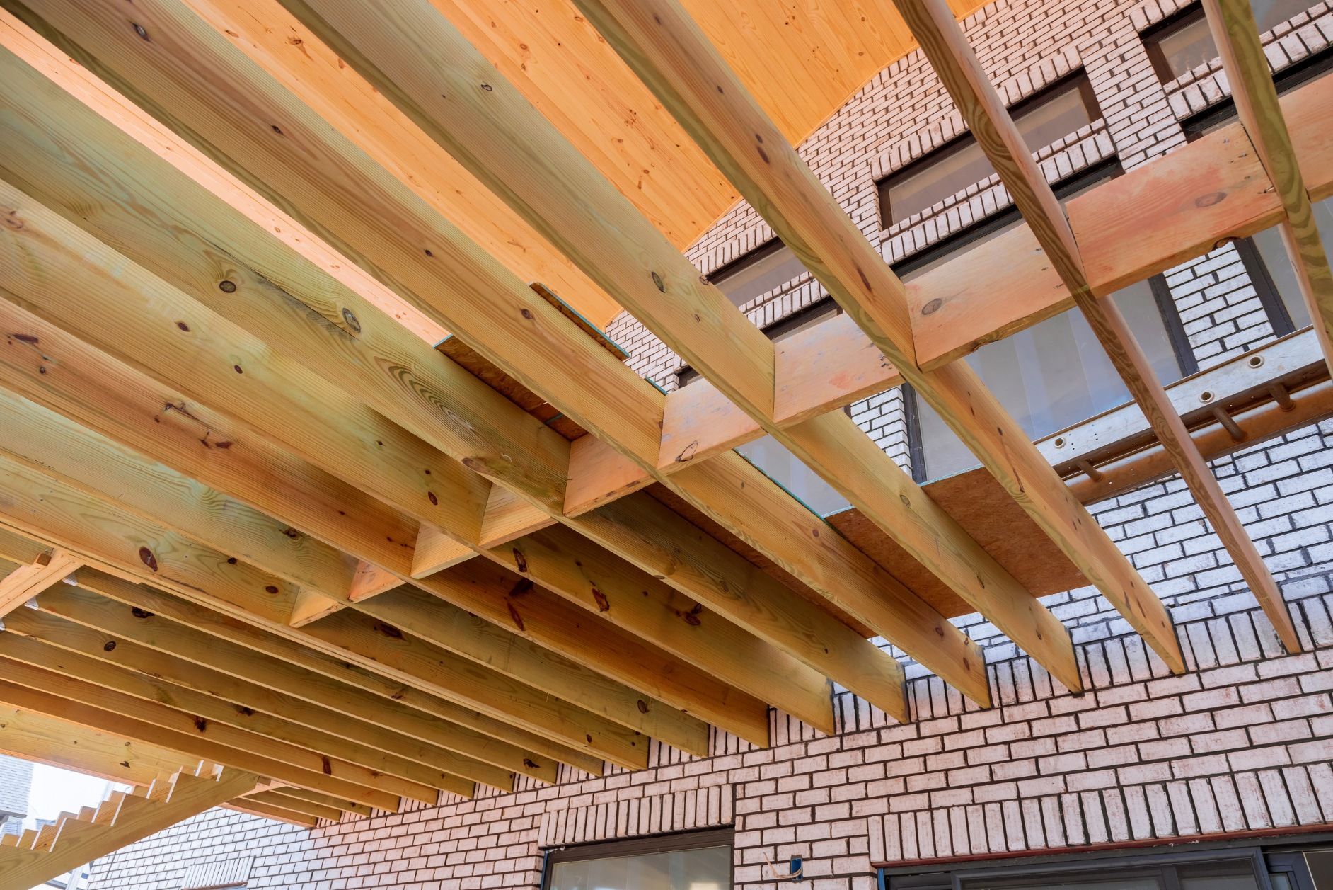 Wooden ceiling joists under construction above a brick wall and open framing.