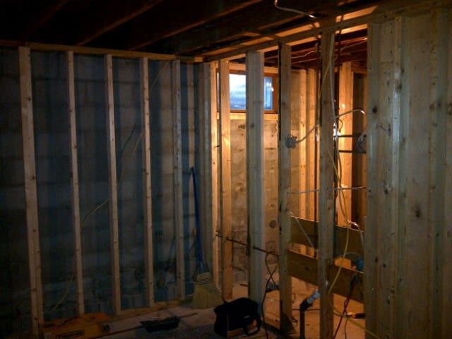 Unfinished room with exposed wooden framing, insulation, and warm light from a window opening