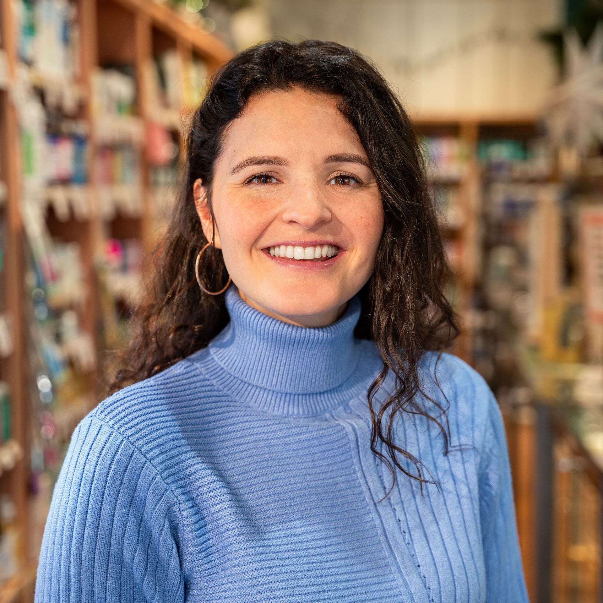 A woman in a blue sweater is smiling in a store.