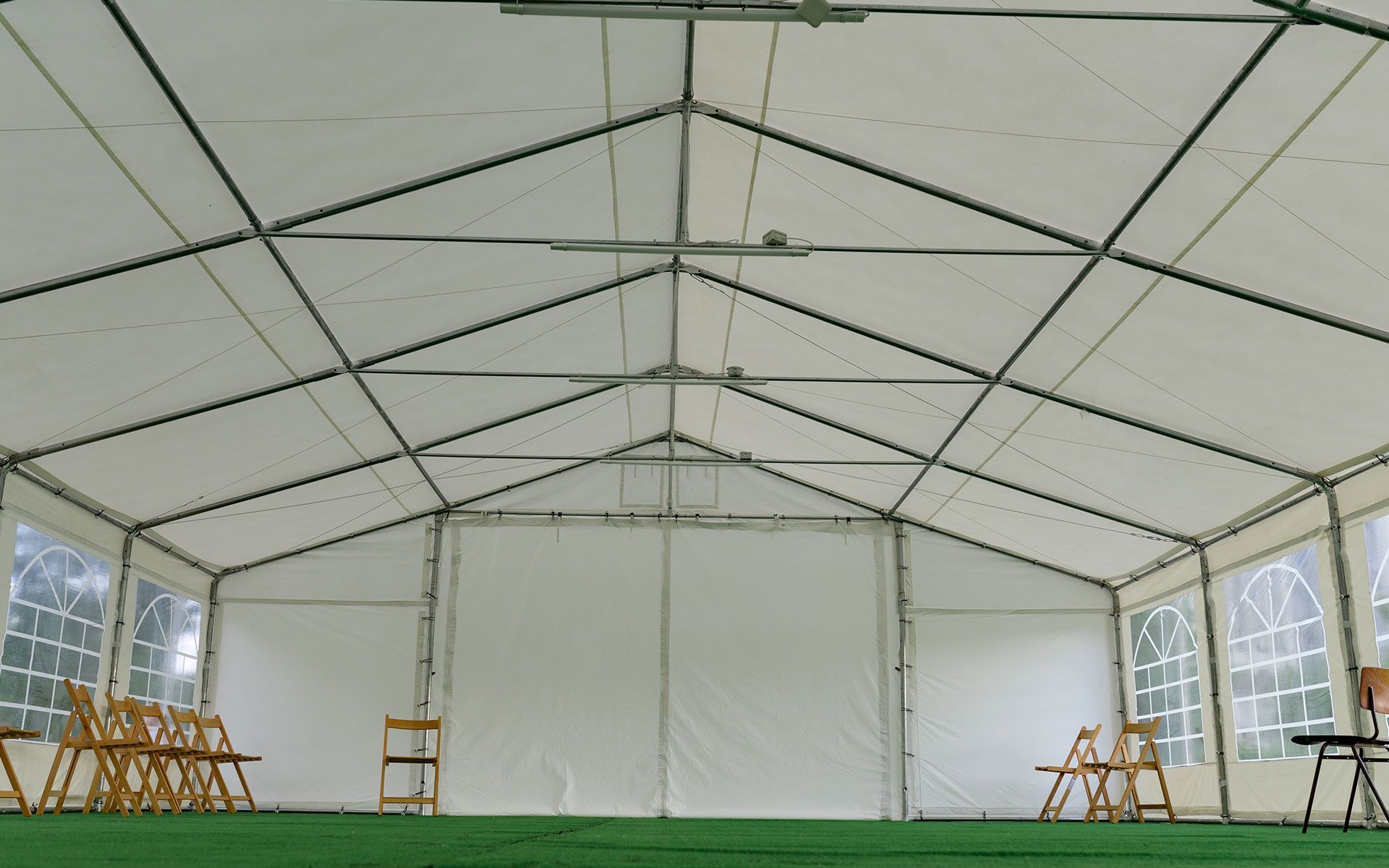A large white tent with chairs and tables inside of it.