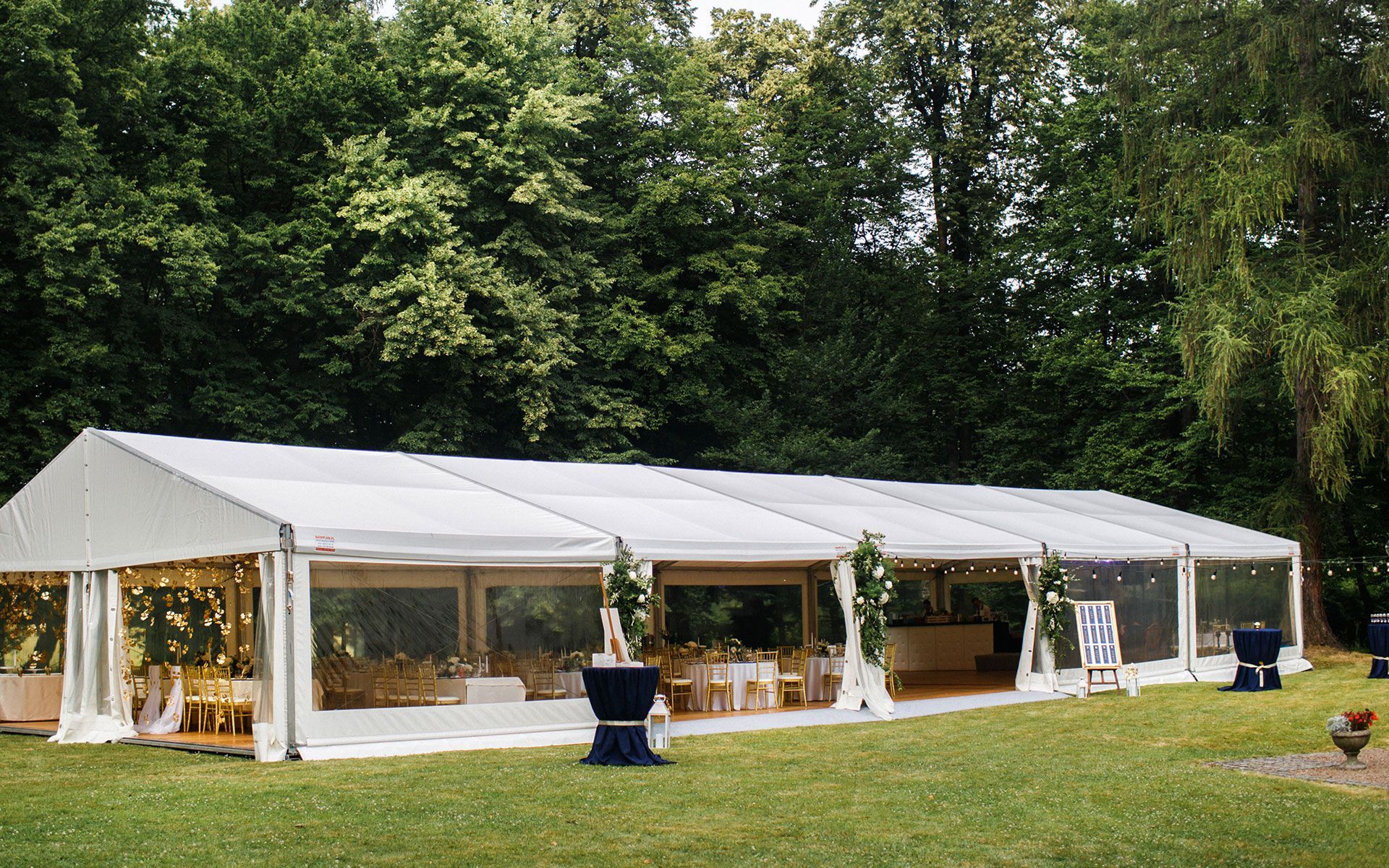 A large white tent is sitting in the middle of a grassy field.