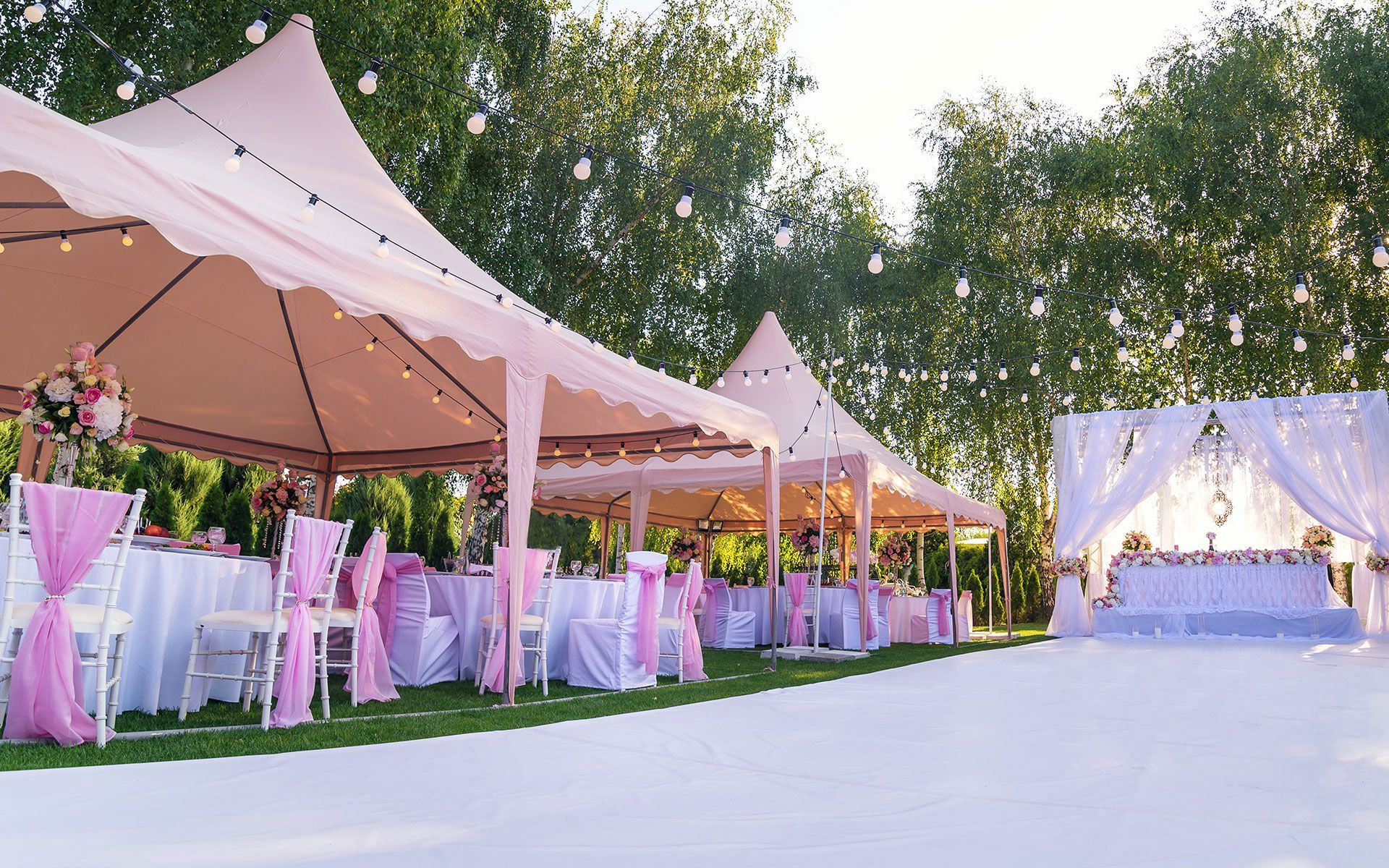 There are many tents and tables set up for a wedding reception.