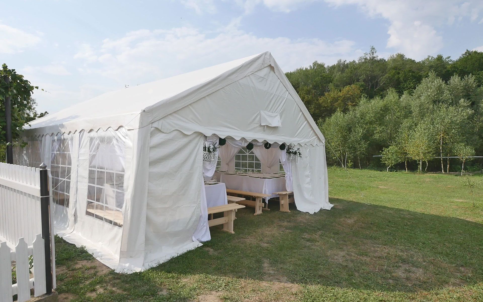 A white tent is sitting in the middle of a grassy field.