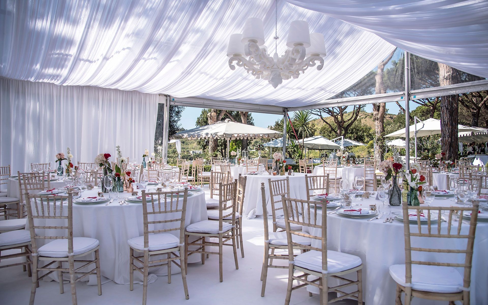 A tent with tables and chairs set up for a wedding reception.