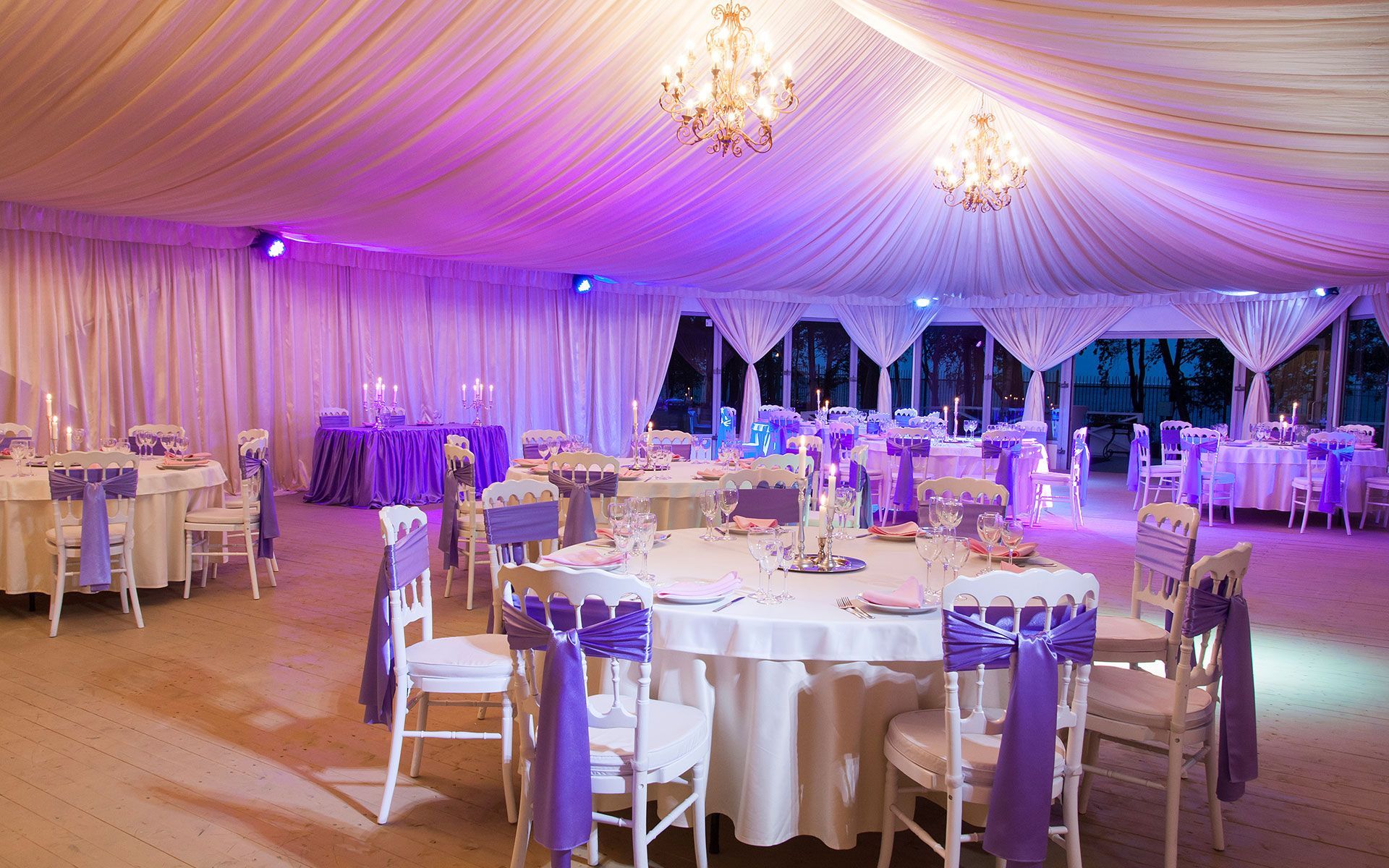 A large room with tables and chairs set up for a wedding reception.