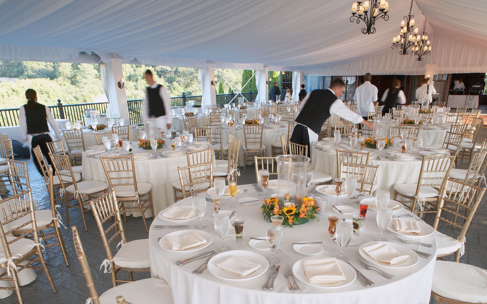 A large tent with tables and chairs set up for a wedding reception