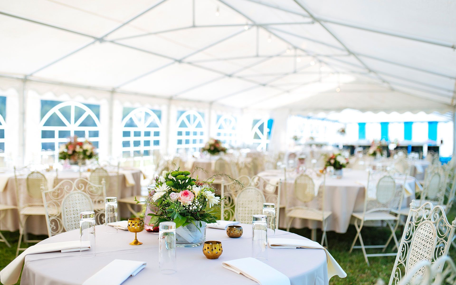 A tent with tables and chairs set up for a wedding reception.
