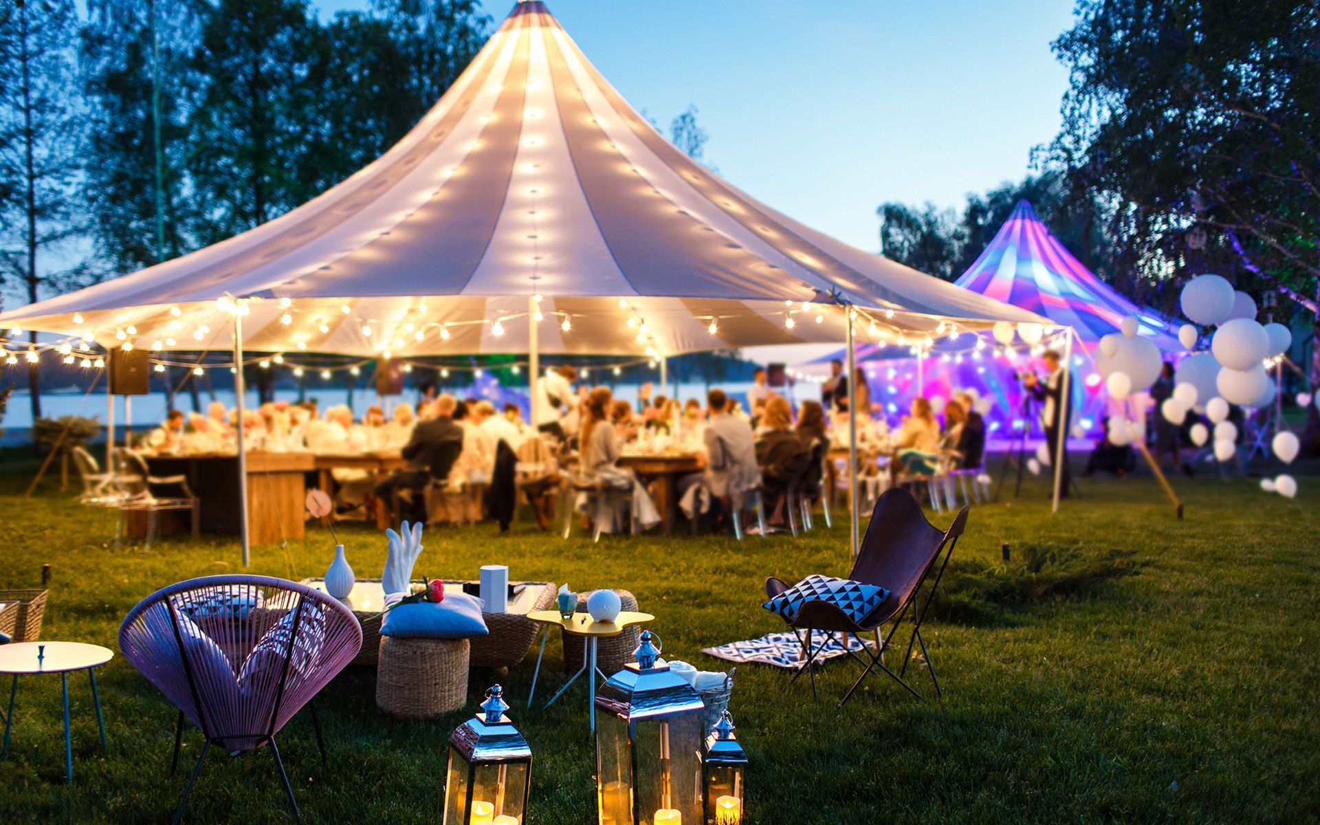 A group of people are sitting at tables under a tent.