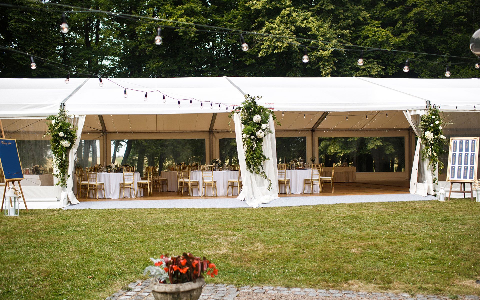A large white tent is sitting in the middle of a lush green field.