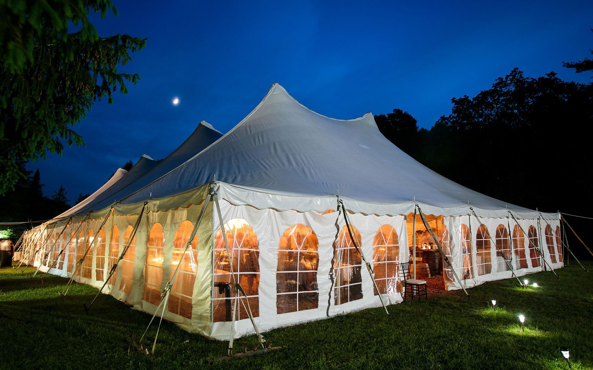 A large white tent is lit up at night in a field.