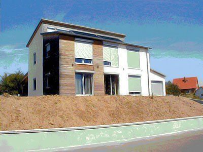 Modernes zweistöckiges Haus mit schrägem Dach und hellgrüner Stützmauer unter blauem Himmel