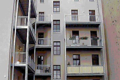 Innenhof eines Mehrfamilienhauses mit Balkonen, Fenstern und Metallstegen