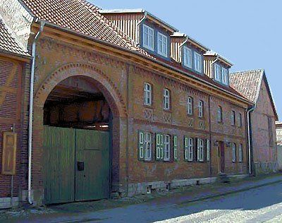 Backsteingebäude mit Bogentor und Dachgauben an einer ruhigen Straße