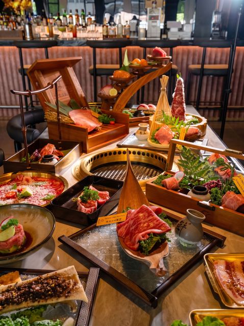 Luxury restaurant table filled with colorful gourmet dishes and cocktails, with a bar in the background