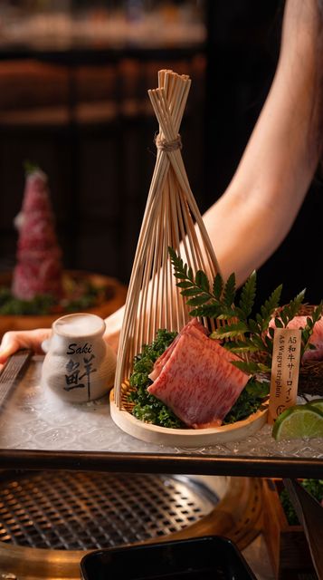 Gourmet plated steak with herbs in a decorative wooden frame on a restaurant tray, with a hand nearby