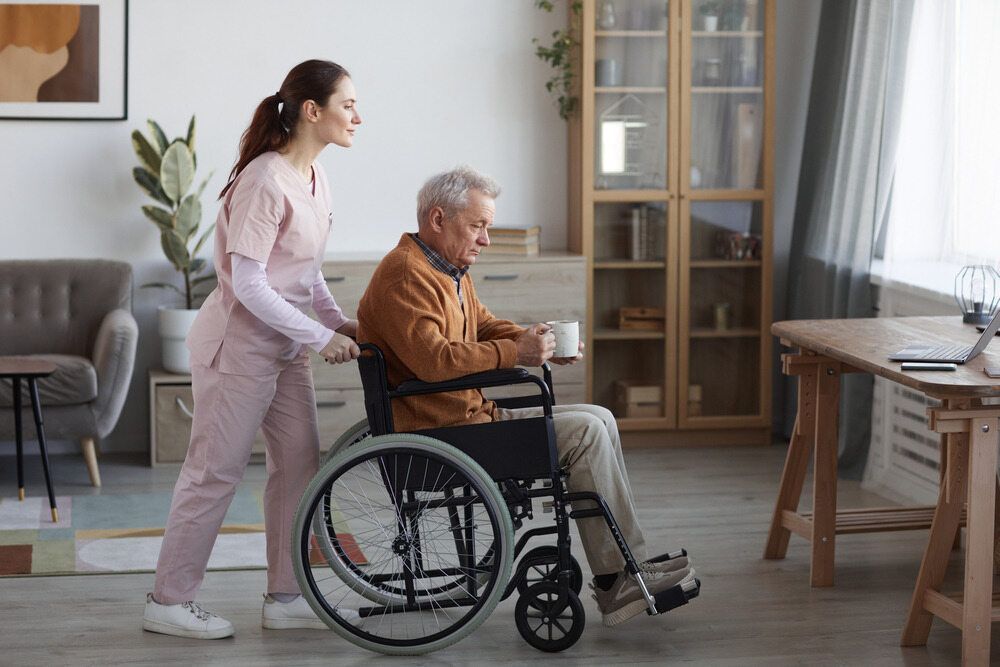 A Woman is Pushing a Man — Empowering You Disability Services In Maryborough, QLD