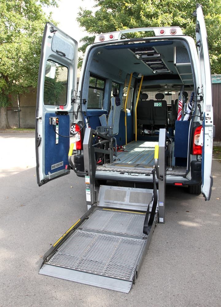 A White Van With a Handicap Ramp is Parked on the Side of the Road — Empowering You Disability Services In Maryborough, QLD