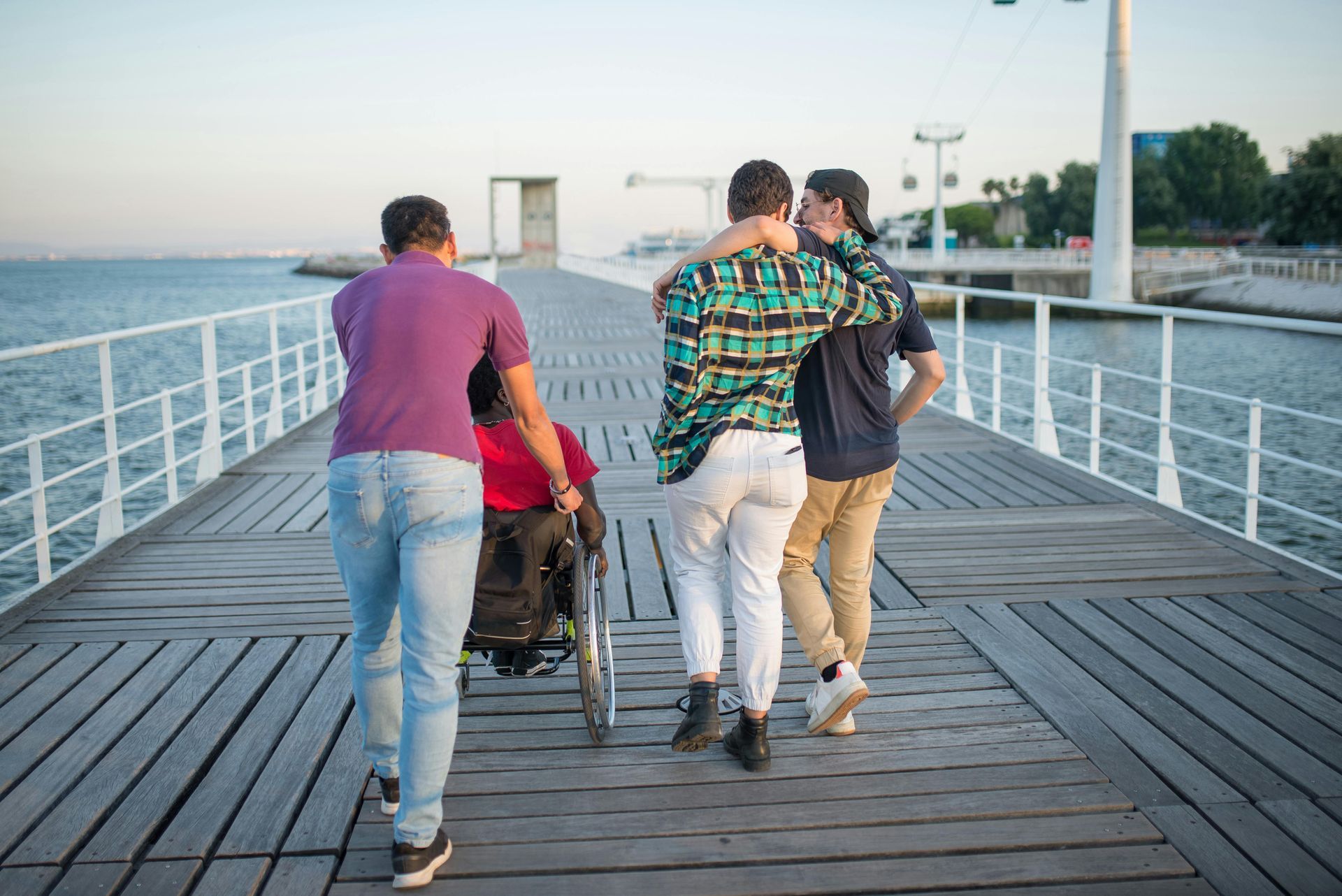 Group of Friends Waking Down a Pier One of Them in a Wheel Chair — Empowering You Disability Services In Maryborough, QLD