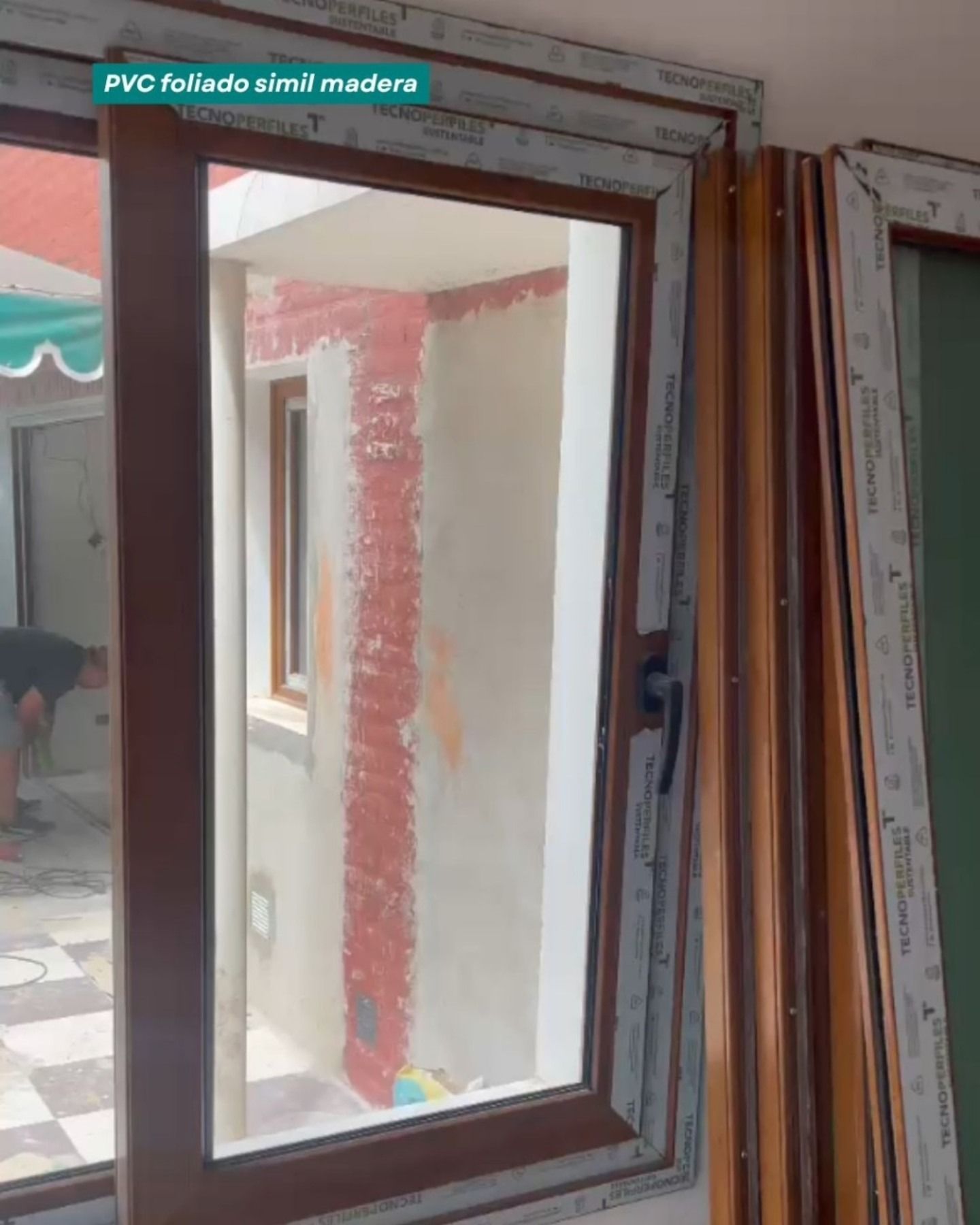 Marco de ventana abierto con un panel de madera apoyado a su lado durante la construcción.