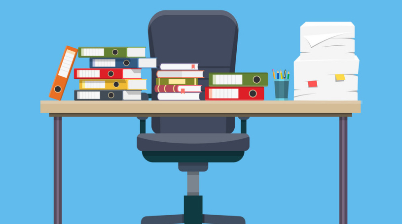 A desk with a chair and a stack of binders on it.