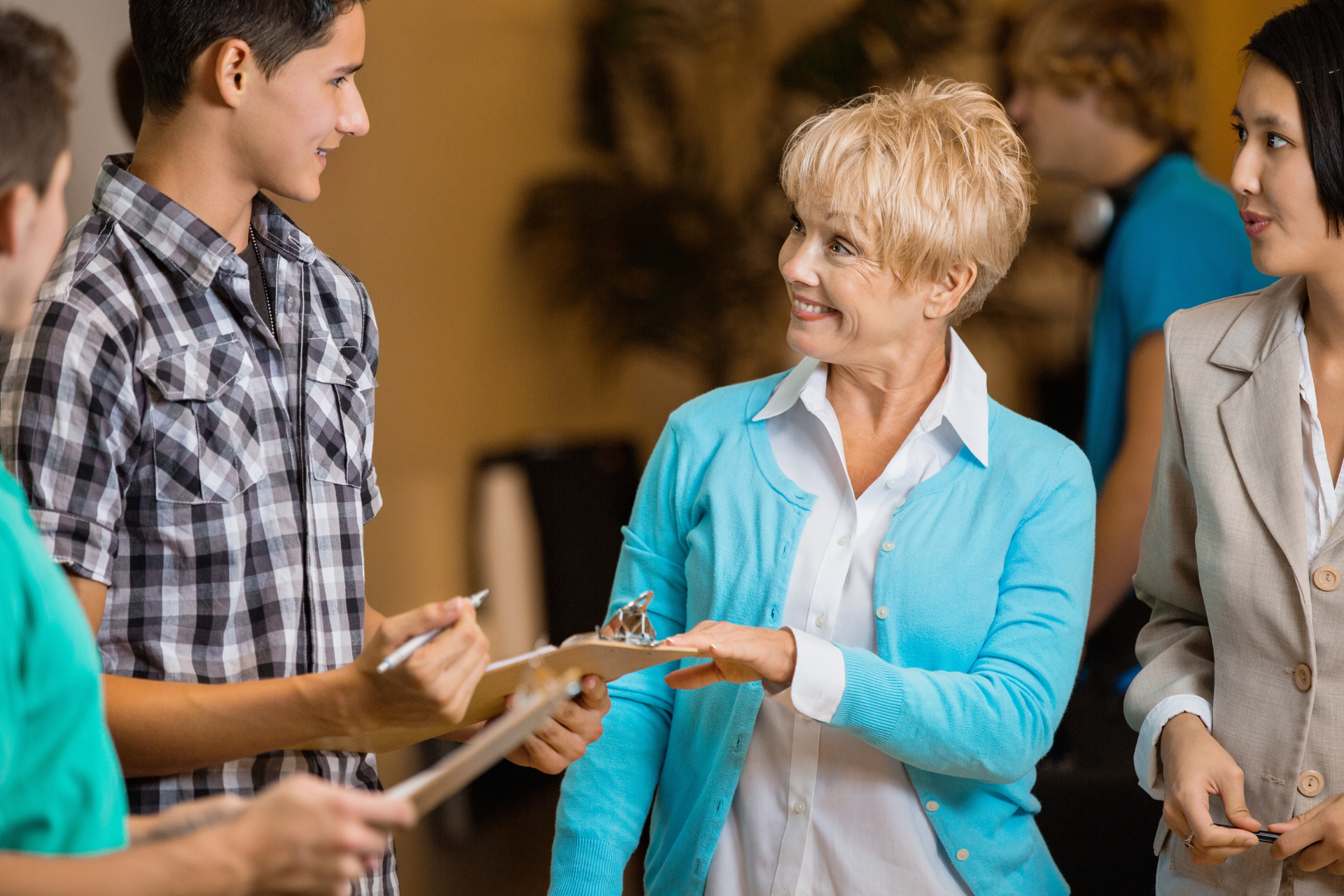 A group of people are standing around a woman holding a clipboard.