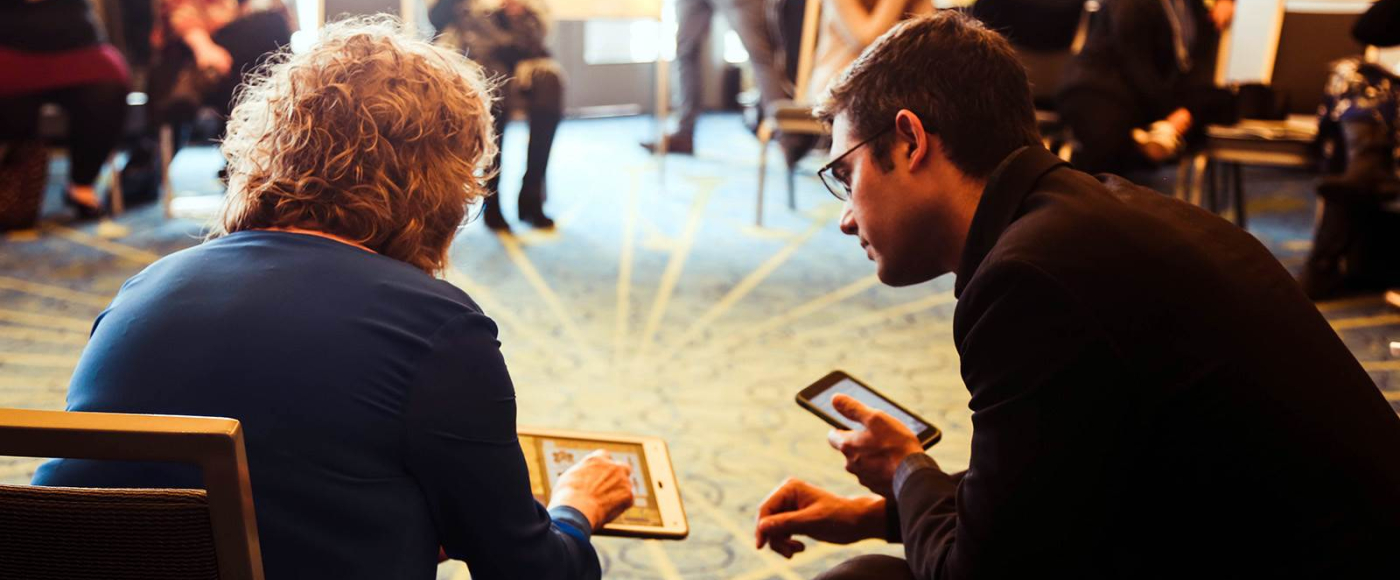 A man and a woman are sitting on the floor looking at their phones.