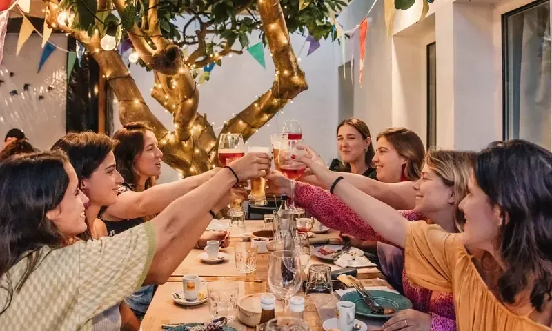 A group raising glasses around a long dinner table