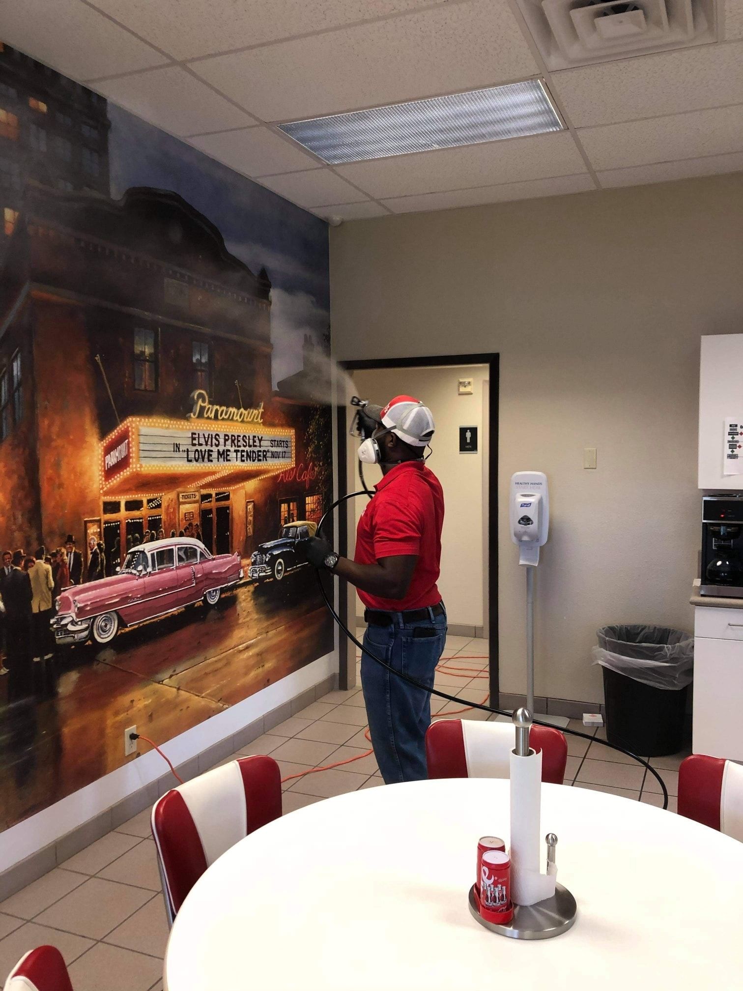 A man in a red shirt is spraying a wall with a hose.