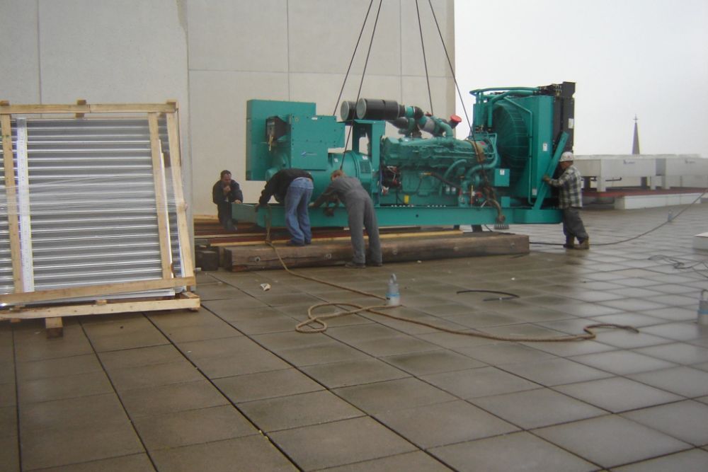 A large green machine is being lifted by a crane